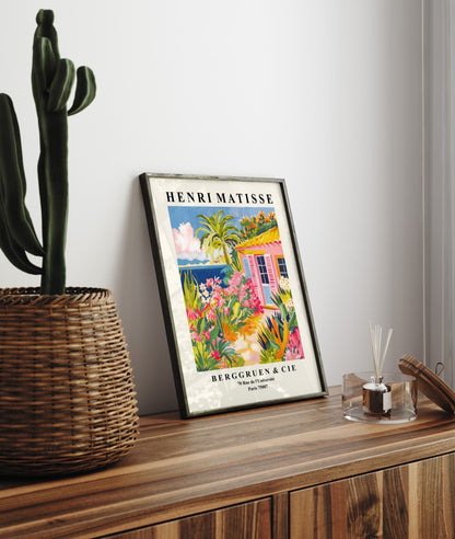 Framed seaside art print of colorful bungalow with lush tropical plants in Matisse style